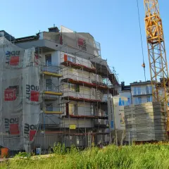 Budowa bloku mieszkalnego z dźwigiem i rusztowaniami.