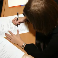 Kobieta pisze na kartce, ucząc się, jak zostać rzeczoznawcą majątkowym.