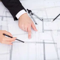 Dwie osoby analizują projekt budowlany, dyskutując, jak zaznaczyć zmiany nieistotne w projekcie.