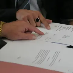 Dwaj mężczyźni analizują dokumenty, jeden wskazuje palcem na wypowiedzenie umowy najmu wzór przez wynajmującego.