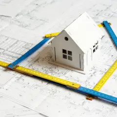 Model domu na planach z miarkami. To wizualizacja, jak może wyglądać wycena opłaty adiacenckiej.
