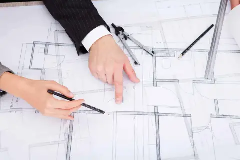 Dwie osoby analizują projekt budowlany, dyskutując, jak zaznaczyć zmiany nieistotne w projekcie.