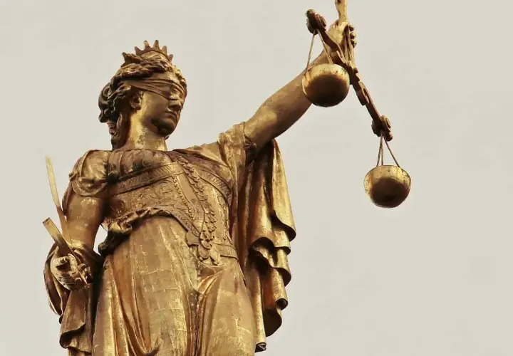 Złota statua Temidy z przepaską na oczach i wagą w dłoni, symbol sprawiedliwości, która może być utrudnianie korzystania z lokalu.