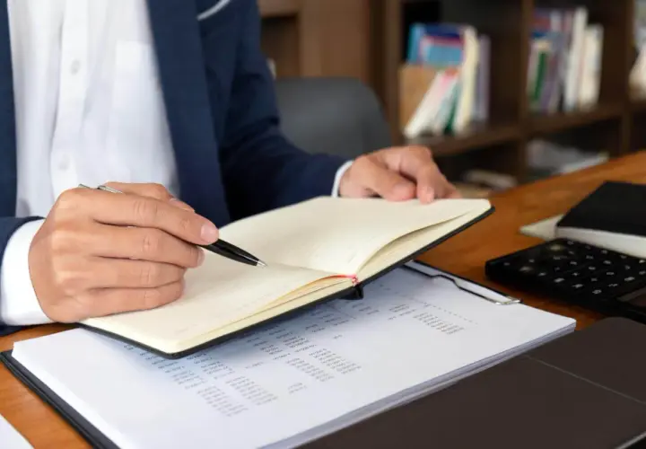 Mężczyzna w garniturze notuje w dzienniku, analizując dokumenty. Szybki odpis księgi wieczystej online ułatwia pracę.
