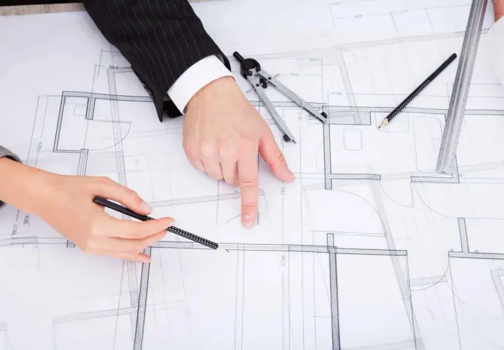 Dwie osoby analizują projekt budowlany, dyskutując, jak zaznaczyć zmiany nieistotne w projekcie.