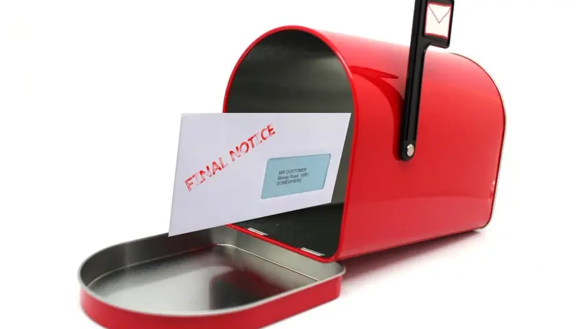 Czerwona skrzynka pocztowa z listem "FINAL NOTICE" - wezwanie do opuszczenia lokalu.