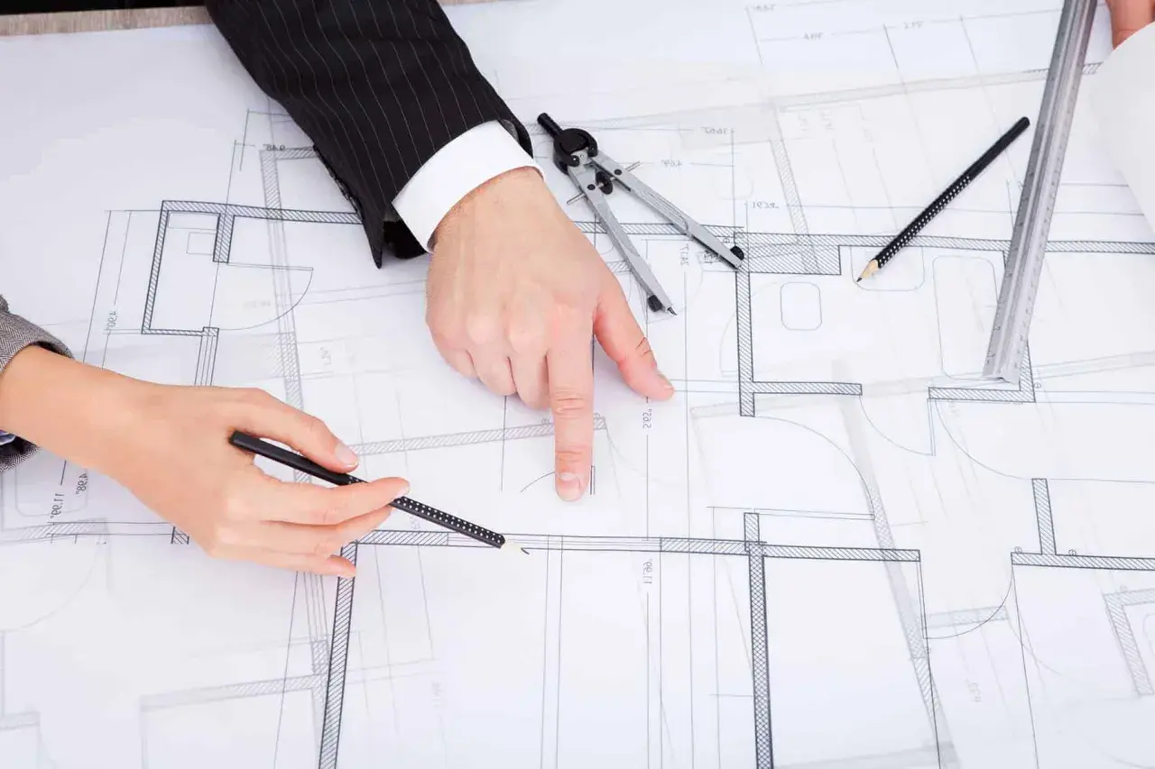 Dwie osoby analizują projekt budowlany, dyskutując, jak zaznaczyć zmiany nieistotne w projekcie.