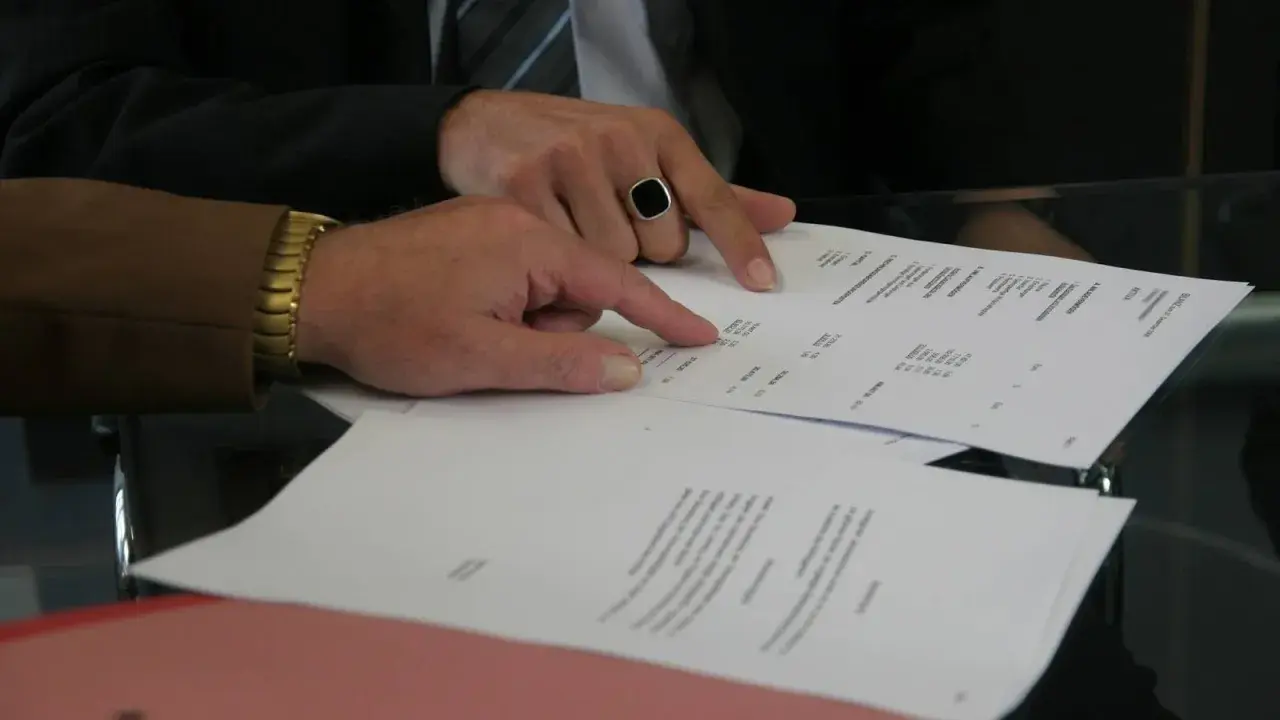 Dwaj mężczyźni analizują dokumenty, jeden wskazuje palcem na wypowiedzenie umowy najmu wzór przez wynajmującego.