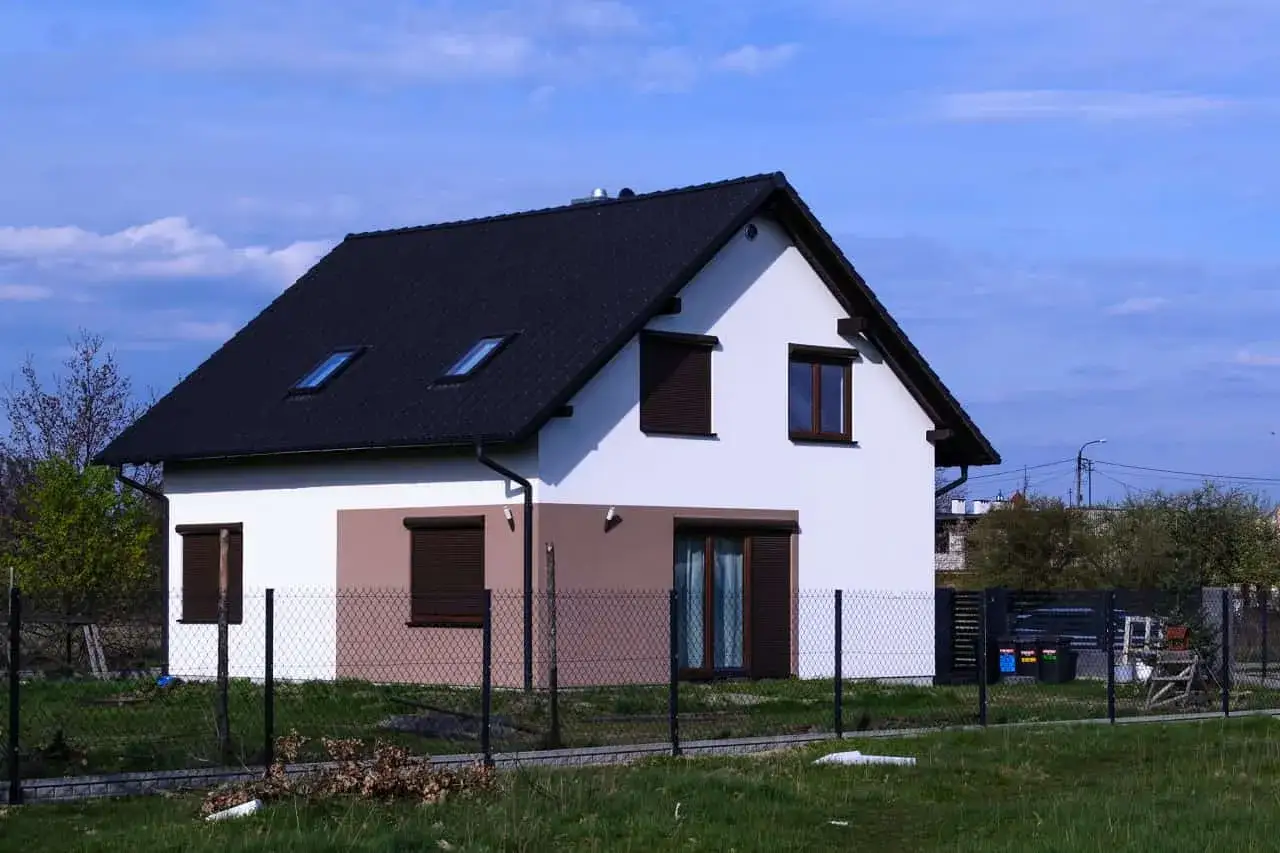 Nowy dom z brązowym dachem i białymi ścianami, częściowo ocieplony. Jak wycenić dom? Zastanów się nad jego stanem i lokalizacją.