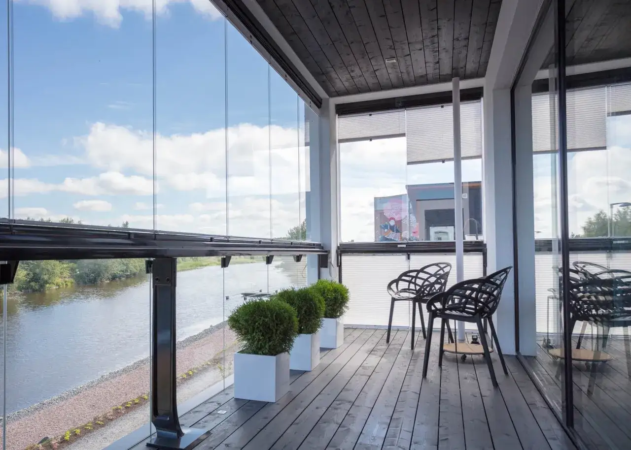 Nowoczesny, przeszklony balkon w bloku z widokiem na rzekę. Idealne miejsce, by odpocząć, gdy już wiesz, jak zabudować balkon w bloku.