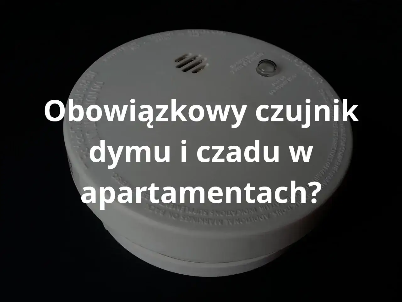 Biały czujnik dymu i czadu w mieszkaniu, zamontowany na suficie. Urządzenie jest okrągłe, z otworami wentylacyjnymi i przyciskiem testowym.